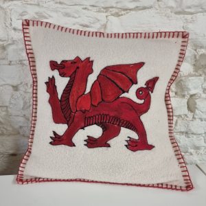 Close-up of white fabric patch with a red dragon embroidery and red blanket-stitch border.