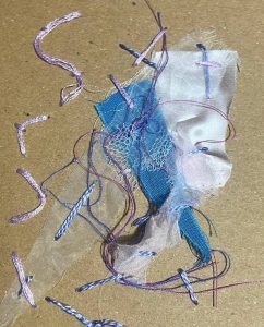 Tangled scraps of blue fabric, white mesh, and purple string laid on a beige background.