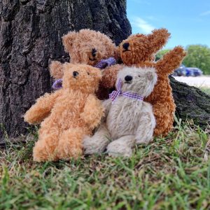 729499514_26930090976687216_9077236437388633361_n | Busy Bees Patchwork Plush teddy bears leaning against a tree outdoors on grass with a blue sky behind them.