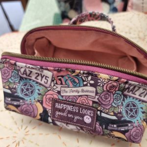 Close-up of a colorful patterned bag with a pink zipper and a label that reads, “Happiness looks good on you.”