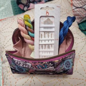 741266037_27050764761286503_8377268848707598359_n | Busy Bees Patchwork Colorful braided cords in pink, rainbow, and blue spilling from a zippered pouch beside a white packaging insert with needles.
