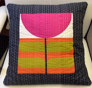 IMG_0435 | Busy Bees Patchwork Decorative quilted throw pillow with a pink semicircle on top, green and orange blocks, and a dark blue patterned border.