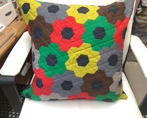 Colorful throw pillow with a geometric flower pattern on a white chair.