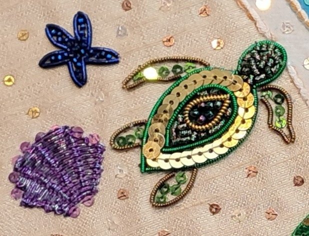 Turtle Finished Design | Busy Bees Patchwork Beaded green and gold turtle appliqué on beige fabric with a blue starfish and purple shell nearby.